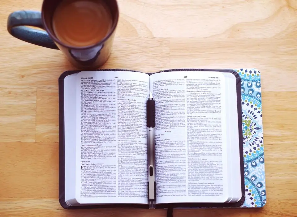 An open Bible beside a cup of coffee