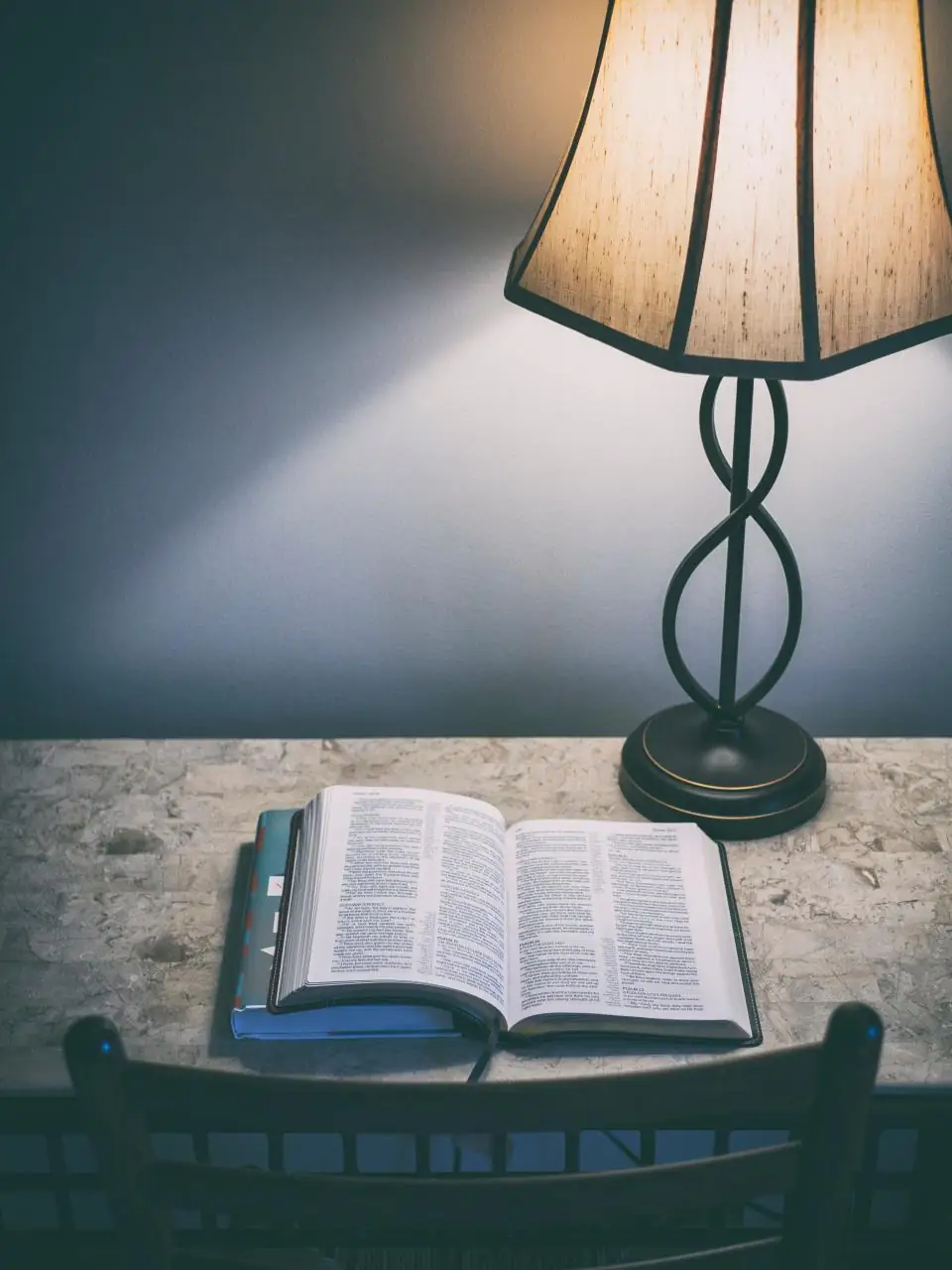 An open Bible on a table under the warm light of a lamp