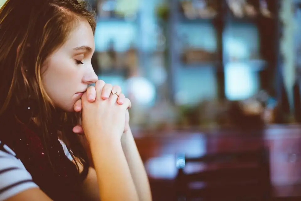 A young woman with head bowed in prayer